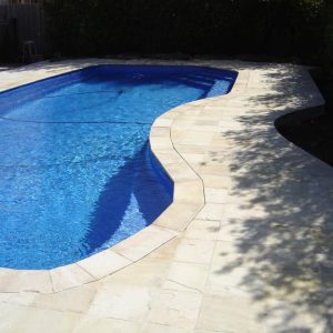 swimming pool surrounded by natural suede sand paving